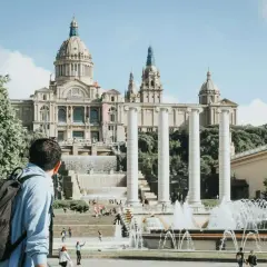Mężczyzna z plecakiem podziwia fontanny i Pałac Narodowy w Barcelonie. Piękna, słoneczna barcelona pogoda listopad.
