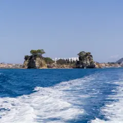Piękna pogoda na Zakynthos w październiku. Błękitne morze, skaliste wysepki i miasteczko w tle. Idealny czas na rejs.