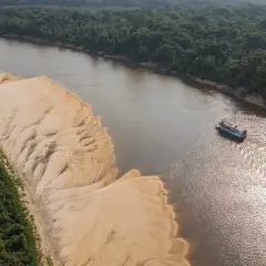 Łódź płynie po szerokiej rzece w Peru, mijając piaszczyste brzegi i gęstą, zieloną dżunglę.