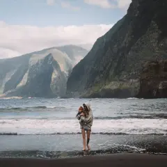 Matka z dzieckiem na plaży, w tle majestatyczne góry. To jedno z madera najpiękniejsze miejsca, gdzie natura zachwyca.
