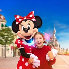 Myszka Miki z dziewczynką na tle zamku w Disneylandzie.