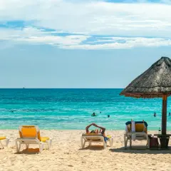 Plaża z leżakami, parasolem i turkusowym morzem.