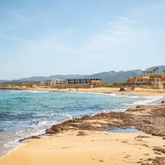 Piękna plaża na Krecie z turkusową wodą i budynkami w tle.