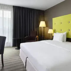 Pokój hotelowy z łóżkiem, biurkiem i fotelem.