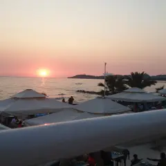 Zachód słońca nad morzem, plaża z parasolami i ludźmi. Idealne miejsce na wakacje, jak sugerują ephesia holiday beach club opinie.