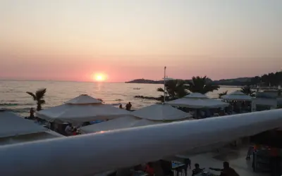 Zachód słońca nad morzem, plaża z parasolami i ludźmi. Idealne miejsce na wakacje, jak sugerują ephesia holiday beach club opinie.