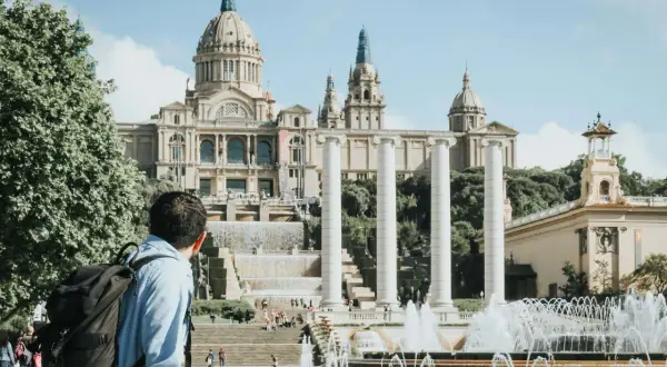 Mężczyzna z plecakiem podziwia fontanny i Pałac Narodowy w Barcelonie. Piękna, słoneczna barcelona pogoda listopad.