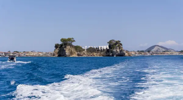 Piękna pogoda na Zakynthos w październiku. Błękitne morze, skaliste wysepki i miasteczko w tle. Idealny czas na rejs.
