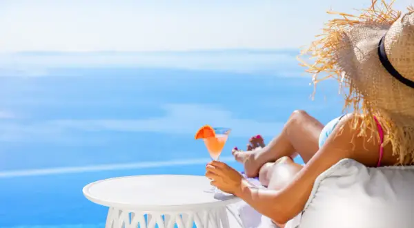 Kobieta w słomkowym kapeluszu relaksuje się z drinkiem przy basenie. Idealny all inclusive soft.