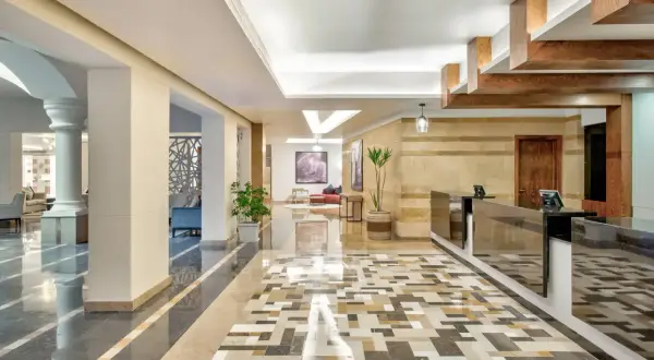 Eleganckie lobby hotelowe z mozaikową podłogą i recepcją. W tle widać wygodne fotele i obrazy, tworząc przyjazną atmosferę dla radisson individuals.