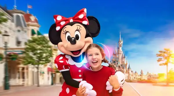 Myszka Miki z dziewczynką na tle zamku w Disneylandzie.