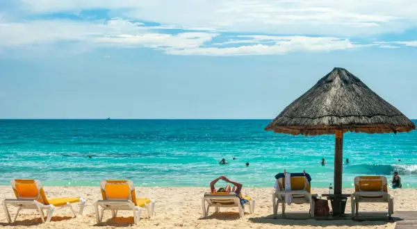 Plaża z leżakami, parasolem i turkusowym morzem.
