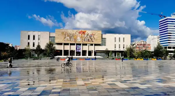 Plac Skanderbega, serce stolicy Albanii, z monumentalnym budynkiem i mozaiką.