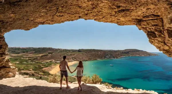 Para w jaskini podziwia widok na turkusowe morze i plażę. Malta w styczniu pogoda jest piękna, idealna na spacer.
