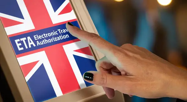 Palec dotyka ekranu z flagą Wielkiej Brytanii i napisem ETA Electronic Travel Authorization. To krok do uzyskania wizy do Anglii.
