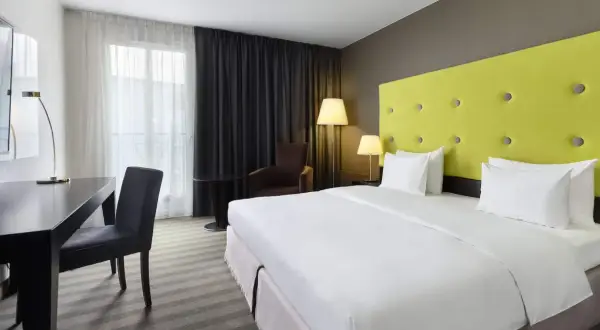 Pokój hotelowy z łóżkiem, biurkiem i fotelem.