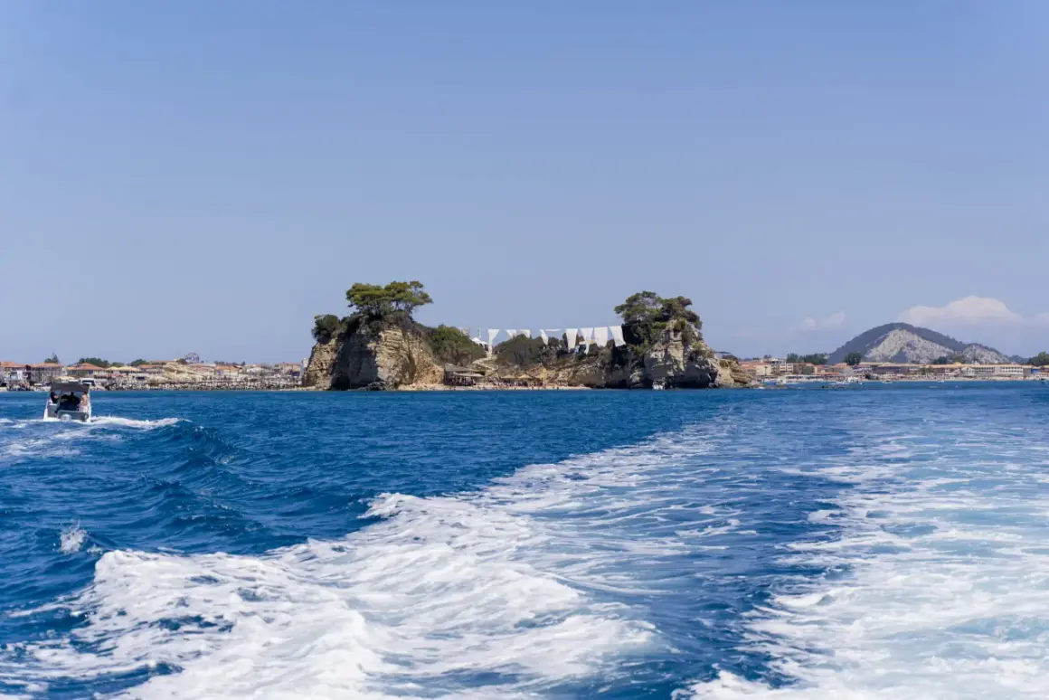 Piękna pogoda na Zakynthos w październiku. Błękitne morze, skaliste wysepki i miasteczko w tle. Idealny czas na rejs.