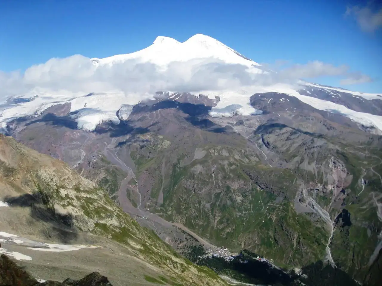 Elbrus, najwyższy szczyt Kaukazu, lśni w słońcu, otoczony lodowcami i skalistymi zboczami.