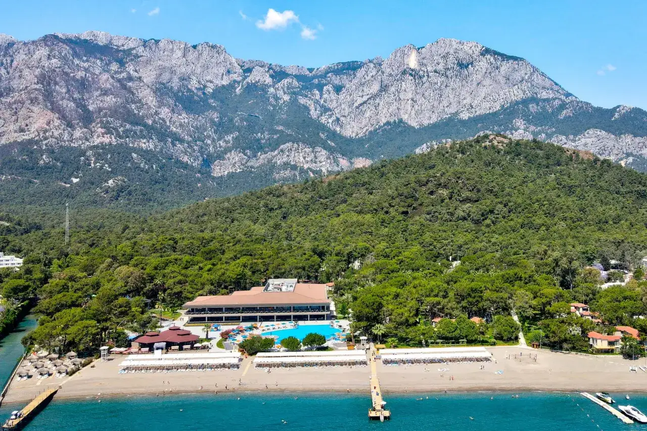 Widok na Kimeros Park Holiday Village z plażą, basenem i górami w tle. Wiele pozytywnych kimeros park holiday village opinie potwierdza urok tego miejsca.