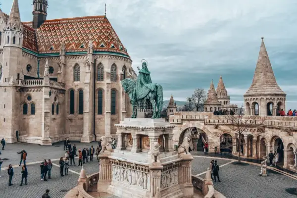 Rynek w Budapeszcie z pomnikiem konnym i Kościołem Macieja. Turyści zwiedzają, zastanawiając się nad cenami w Budapeszcie.