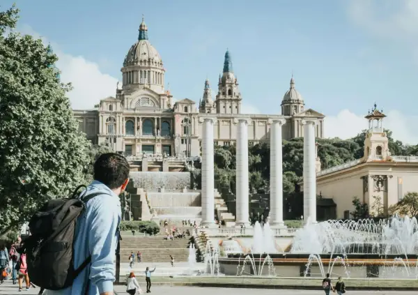 Mężczyzna z plecakiem podziwia fontanny i Pałac Narodowy w Barcelonie. Piękna, słoneczna barcelona pogoda listopad.