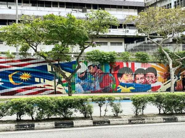 Kolorowy mural z flagą Malezji i uśmiechniętymi dziećmi. Wiza do Malezji może być pierwszym krokiem do zobaczenia tego piękna.