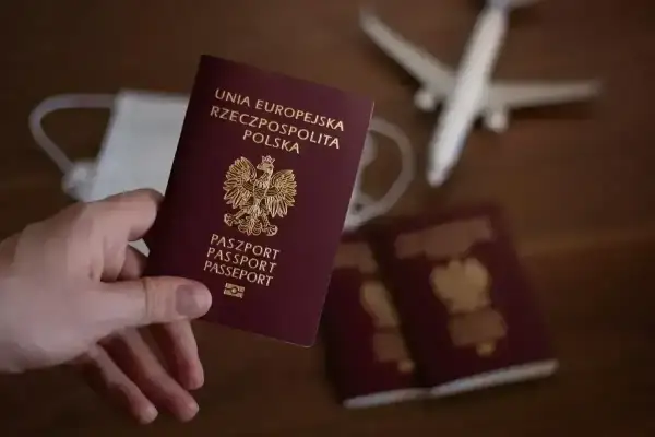 Paszport jest niezbędny, by podróżować do Anglii. Na zdjęciu polski paszport, maseczka i samolot.