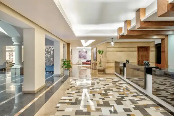 Eleganckie lobby hotelowe z mozaikową podłogą i recepcją. W tle widać wygodne fotele i obrazy, tworząc przyjazną atmosferę dla radisson individuals.