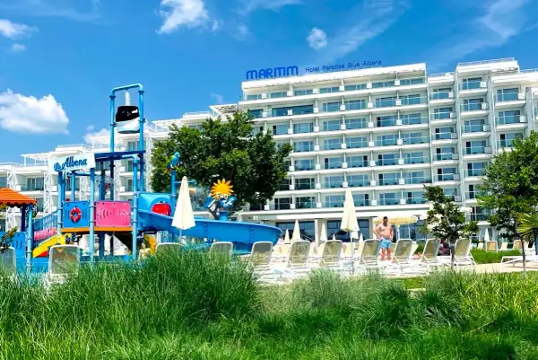 Hotel Paradise Blue Albena z placem zabaw wodnym i leżakami na tle błękitnego nieba.