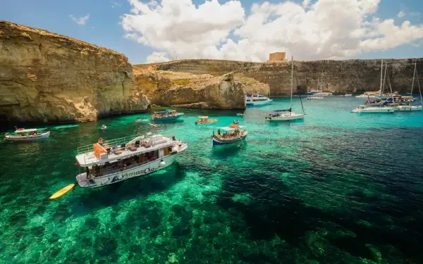 Malta, wrzesień: turkusowa woda, klify i łodzie w Zatoce Błękitnej. Idealna pogoda na rejs.