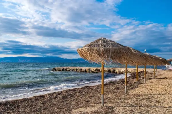 Słomiane parasole na plaży, idealne na relaks. Warto przeczytać angela beach opinie przed podróżą.