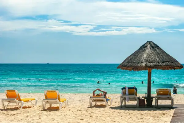 Plaża z leżakami, parasolem i turkusowym morzem.
