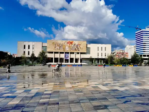 Plac Skanderbega, serce stolicy Albanii, z monumentalnym budynkiem i mozaiką.