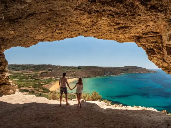 Para w jaskini podziwia widok na turkusowe morze i plażę. Malta w styczniu pogoda jest piękna, idealna na spacer.