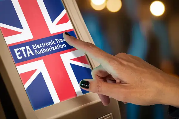 Palec dotyka ekranu z flagą Wielkiej Brytanii i napisem ETA Electronic Travel Authorization. To krok do uzyskania wizy do Anglii.