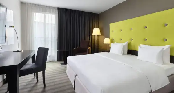 Pokój hotelowy z łóżkiem, biurkiem i fotelem.