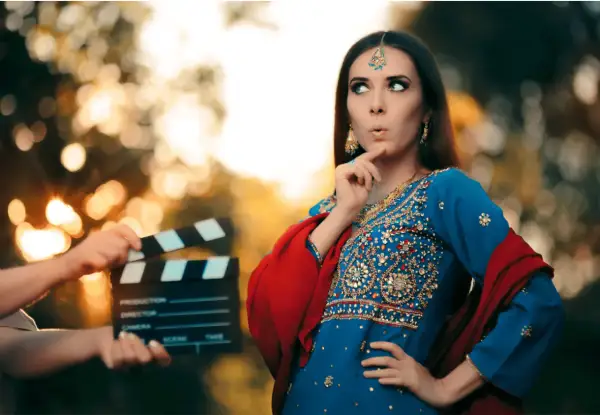 Kobieta w tradycyjnym indyjskim stroju i klaps filmowy na planie.